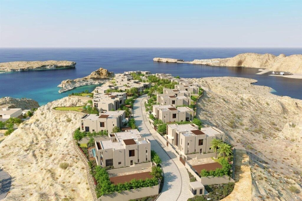 Aerial view of a coastal residential development featuring modern villas surrounded by rocky hills and turquoise waters.
